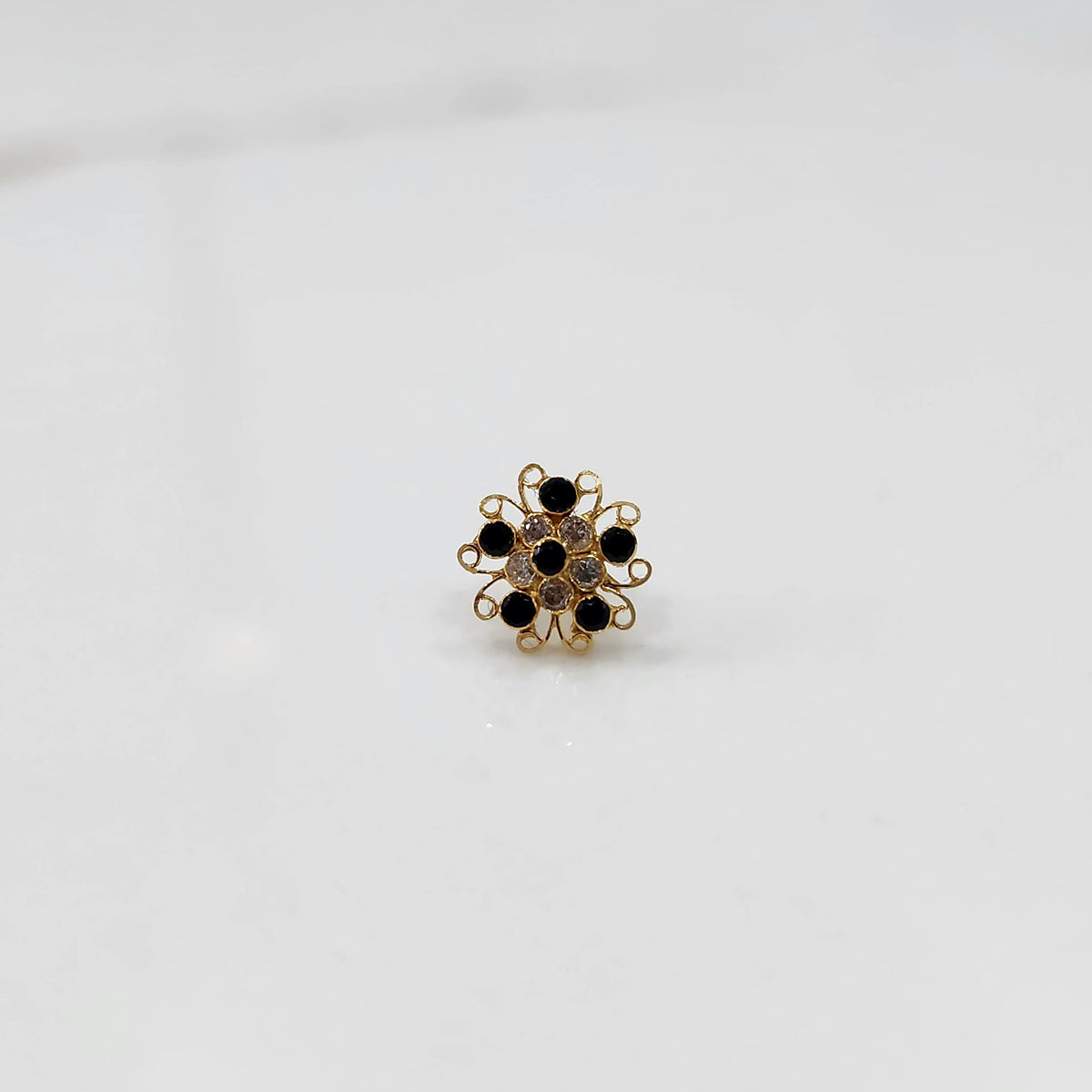 Gold nose pin with black round-cut stones and ornate swirl border