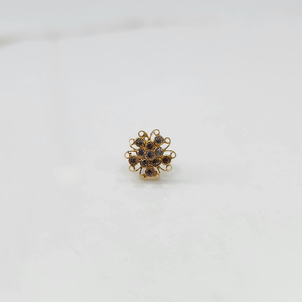 Gold nose pin with champagne round-cut stones and ornate swirl border