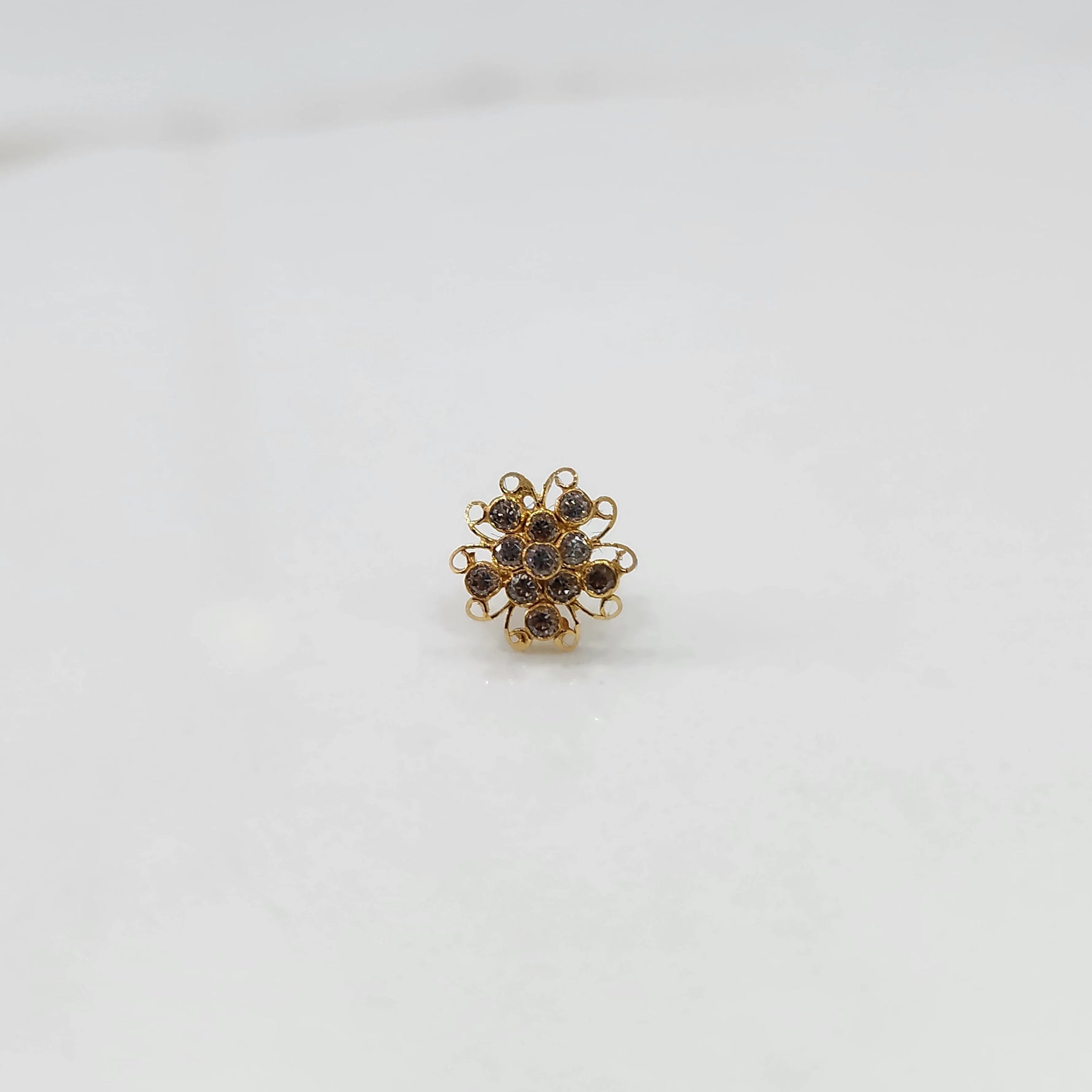Gold nose pin with champagne round-cut stones and ornate swirl border