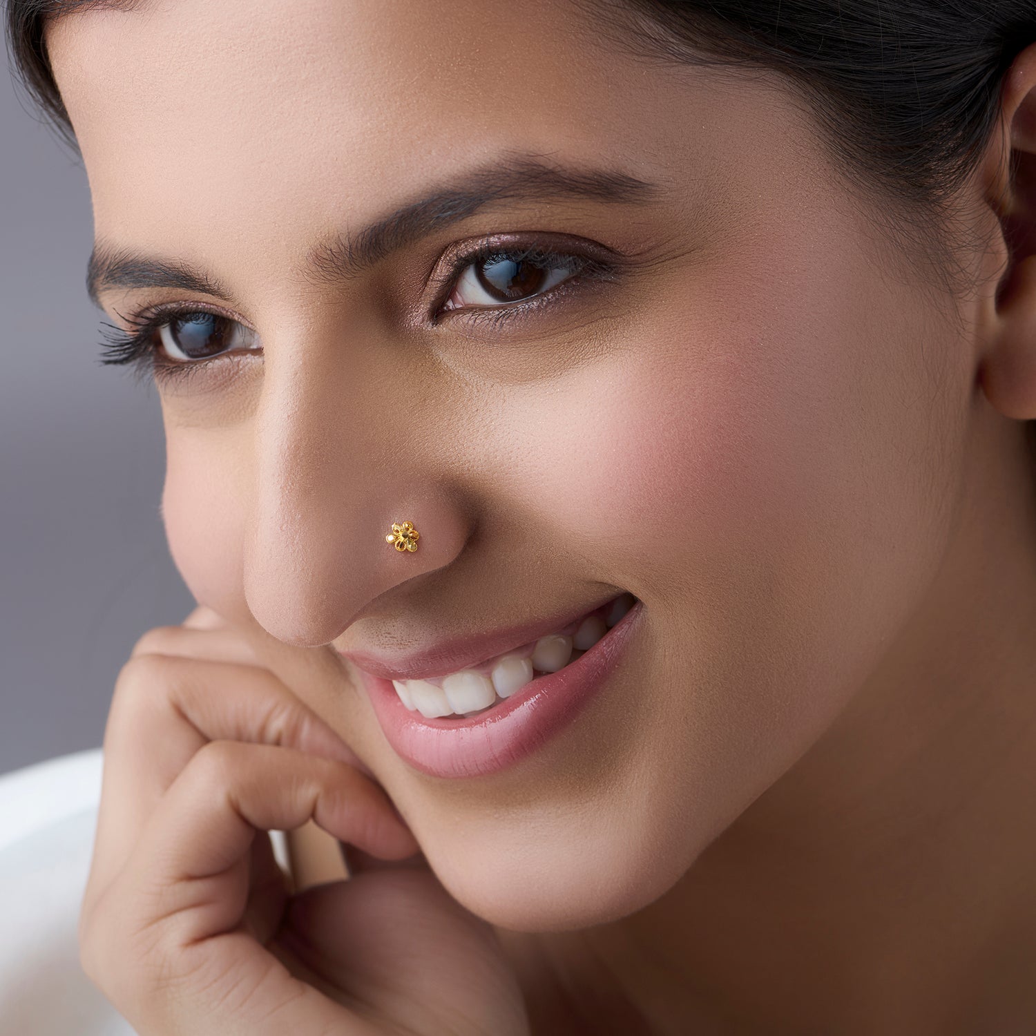 Close-up of a smiling woman wearing a delicate gold nose pin
