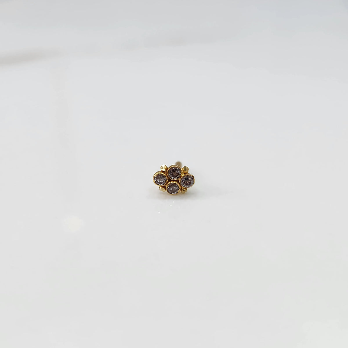Women's gold nose pin design with subtle diamond floral cluster on white background