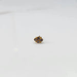 Women's gold nose pin design with subtle diamond floral cluster on white background