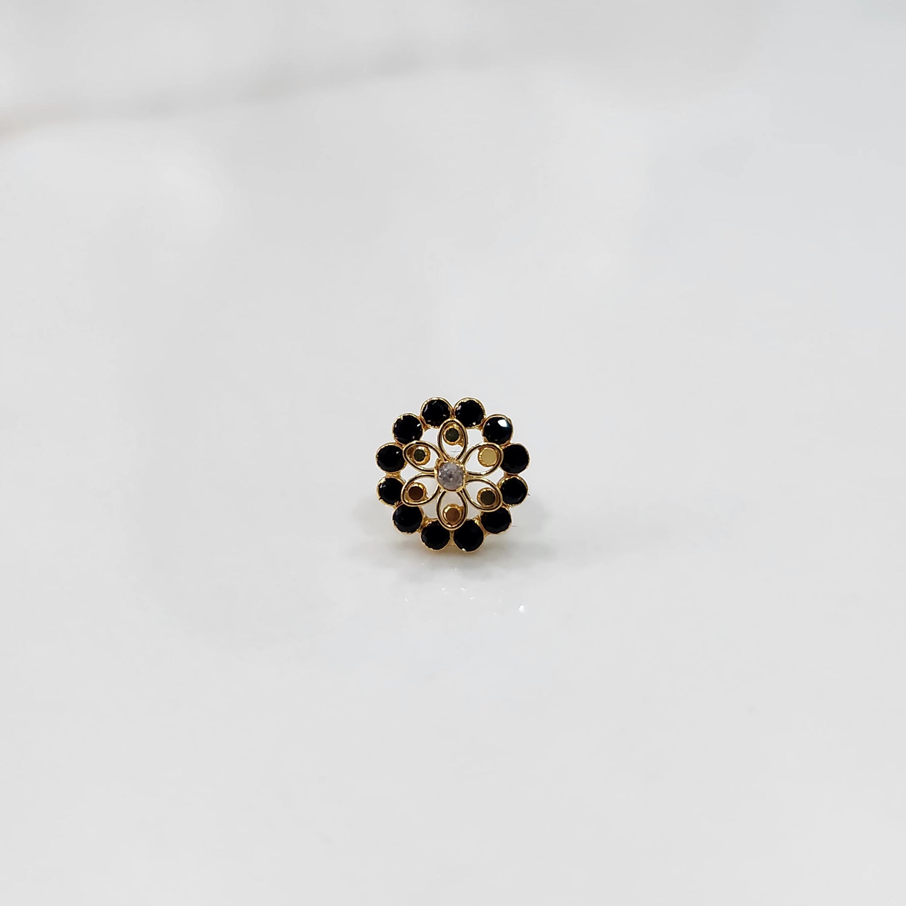 Gold nose pin design with black stone floral cluster on white background