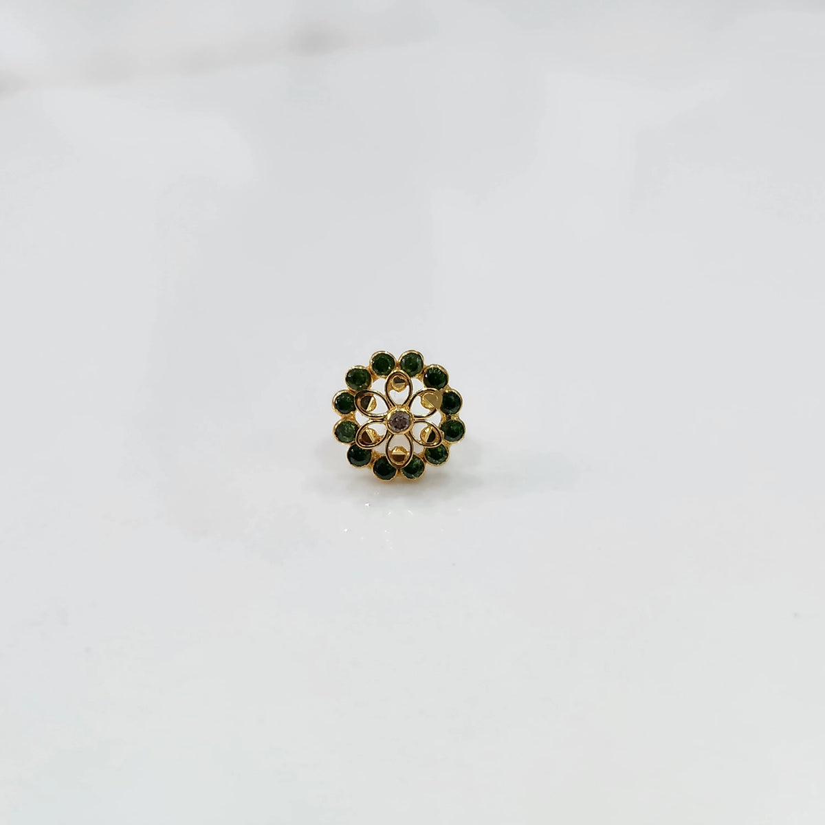 Gold nose pin design with green stone floral cluster on white background