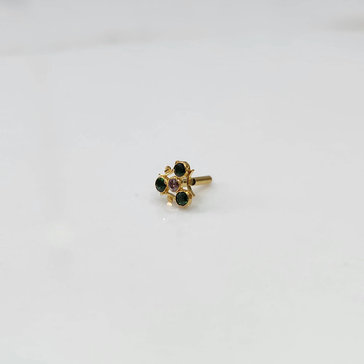 Gold nose pin with green and purple stones in organic branch-style setting