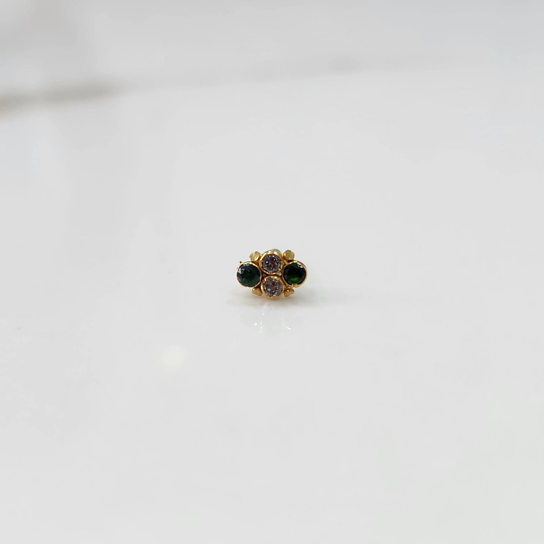 Gold nose pin with small green and purple stone cluster