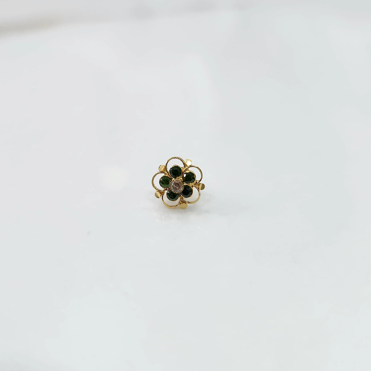 Gold floral nose pin with green stones and clear center stone