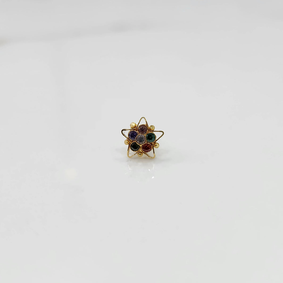 Nose pin design gold with green and red stones in floral pattern on white background