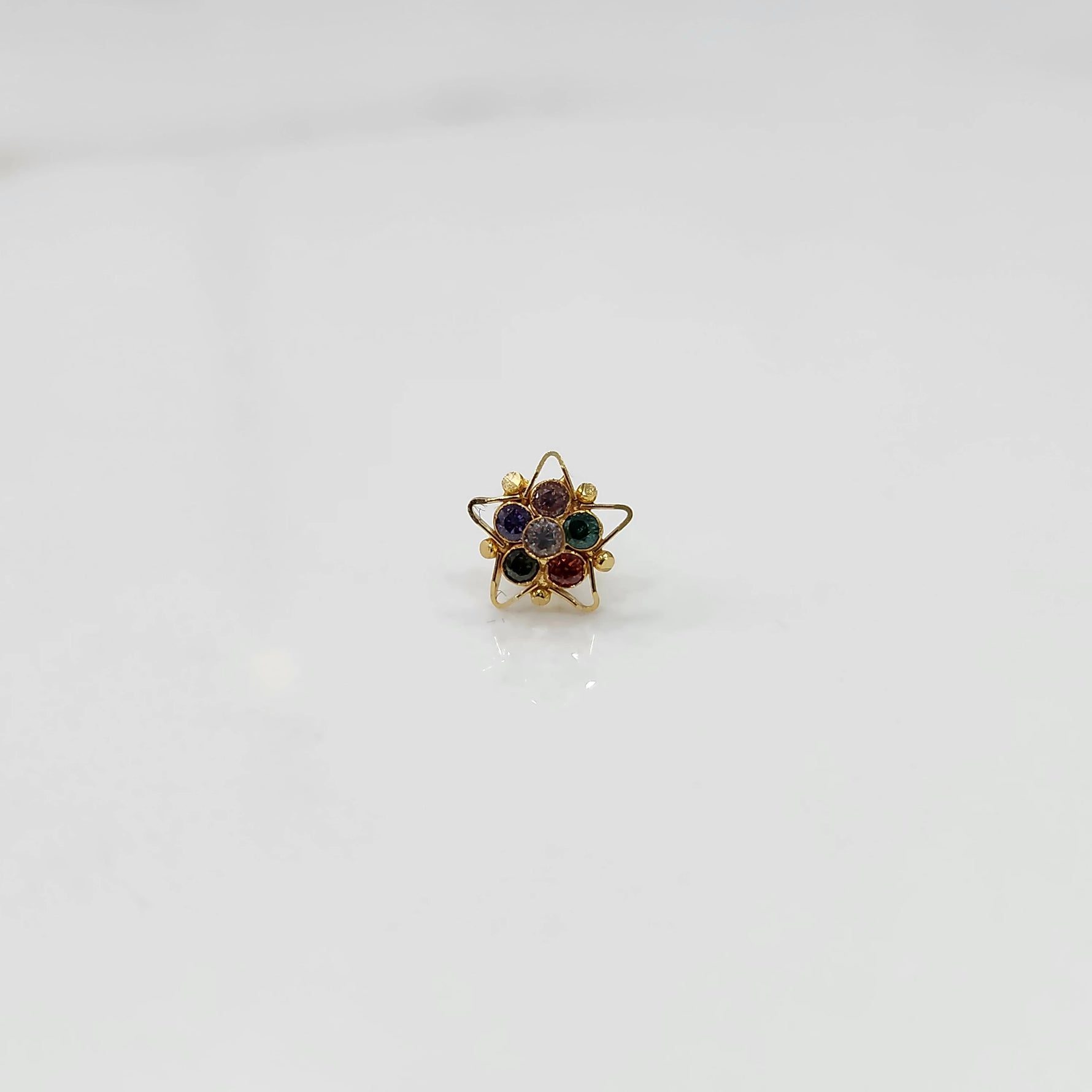 Nose pin design gold with green and red stones in floral pattern on white background