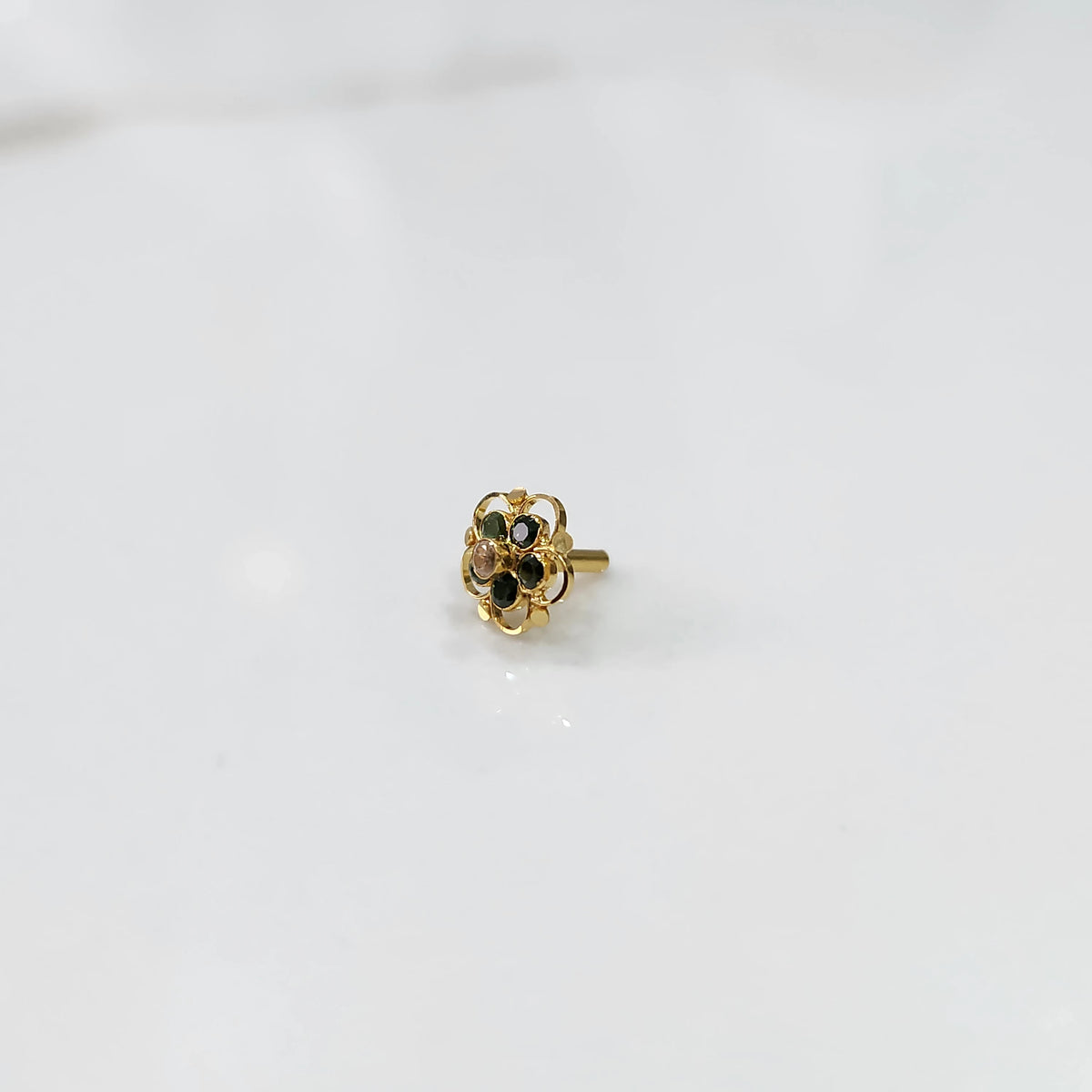 Gold floral nose pin with multicolor gemstones and open swirl border