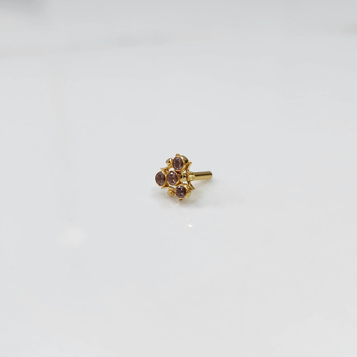 Tiny nose pin gold with delicate floral gemstone cluster on white background