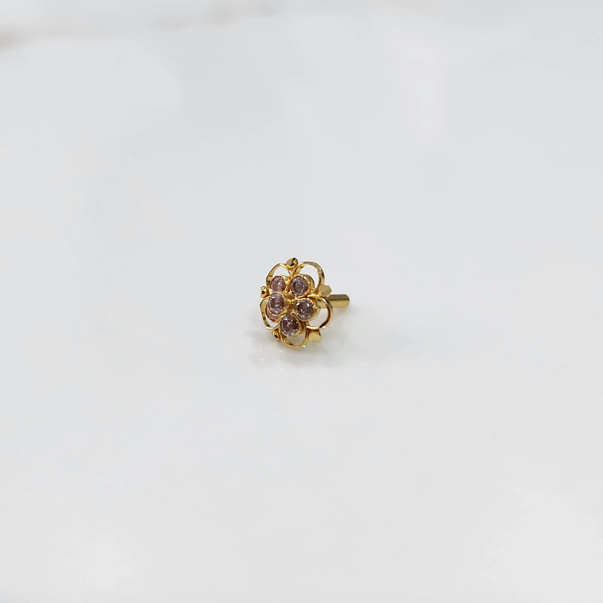 Gold floral nose pin with pink stones and open swirl border
