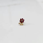 Traditional gold nose stud with ruby outer stones and clear center, decorative gold swirl below