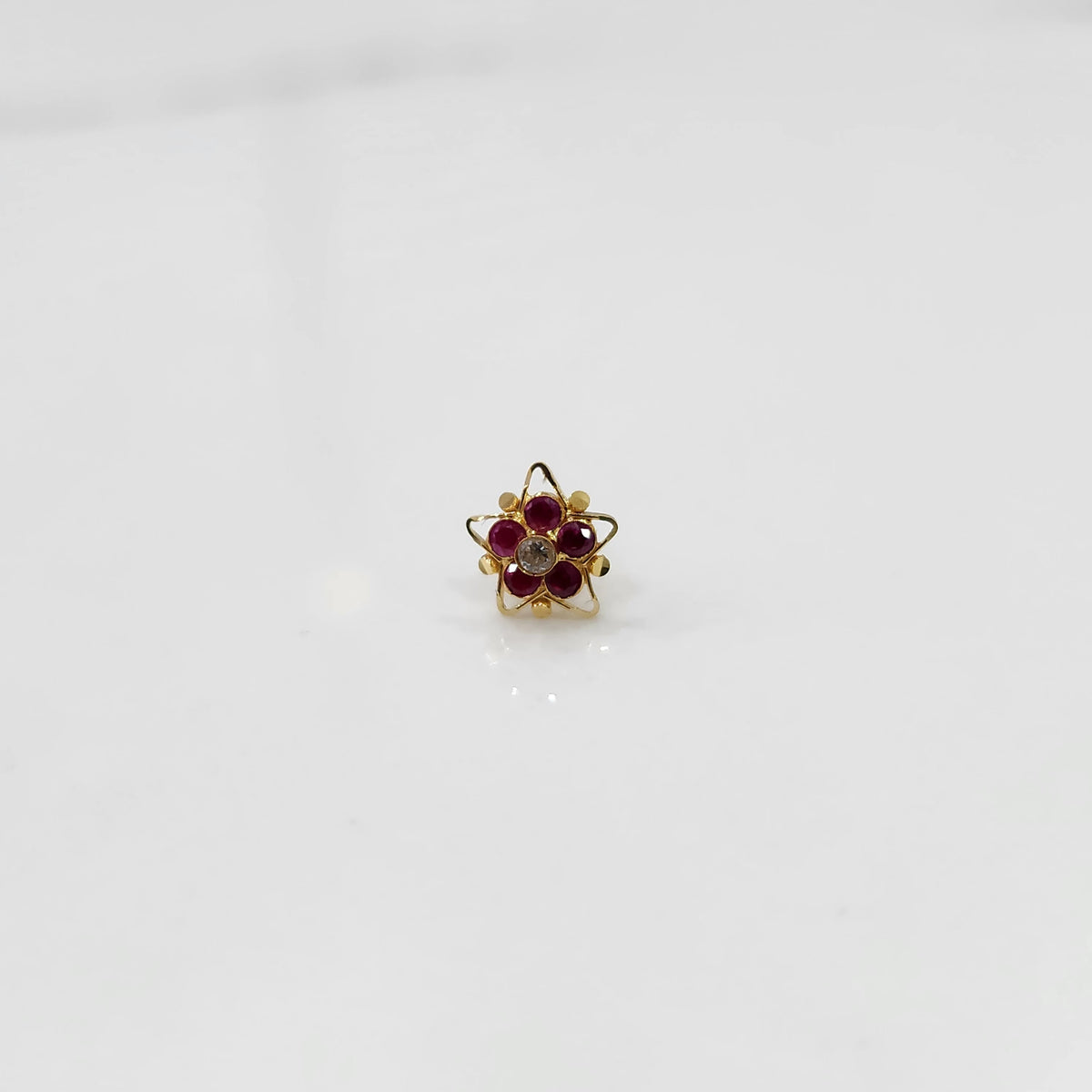 Gold nose pin with ruby stones and clear center in star-shaped petal border