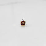 Gold nose pin with ruby stones and clear center in star-shaped petal border