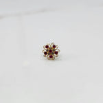 Gold nose pin with ruby and clear round-cut stones in open swirl border