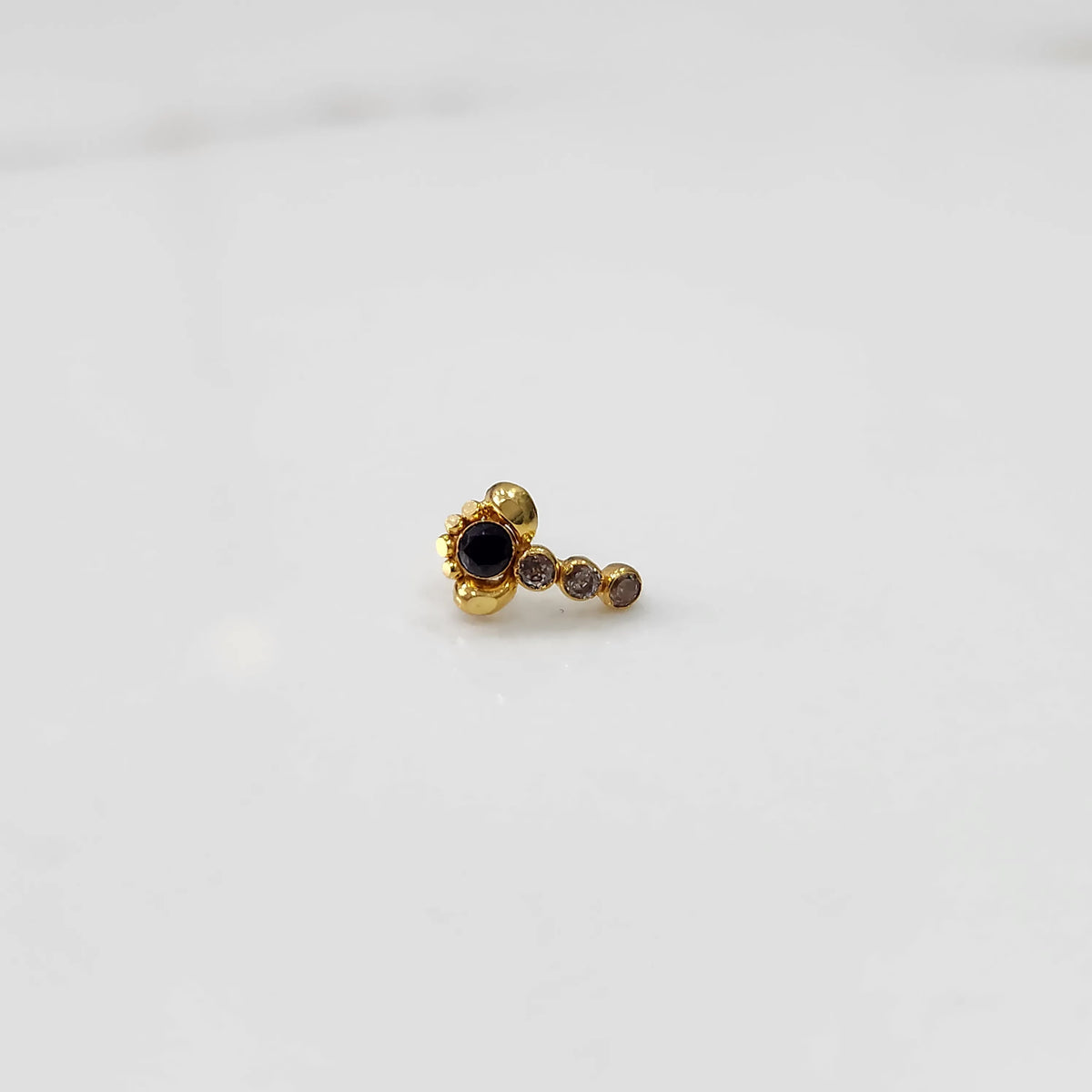 Gold nose pin with black floral head and linear stone trail