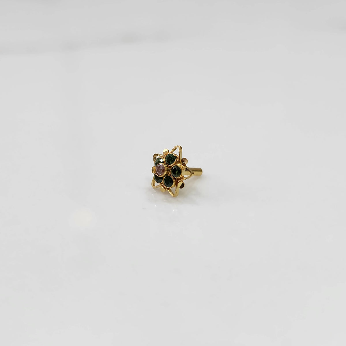 Gold nose pin with green stones and purple center in star-shaped petal border