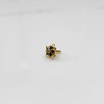 Gold nose pin with green stones and purple center in star-shaped petal border