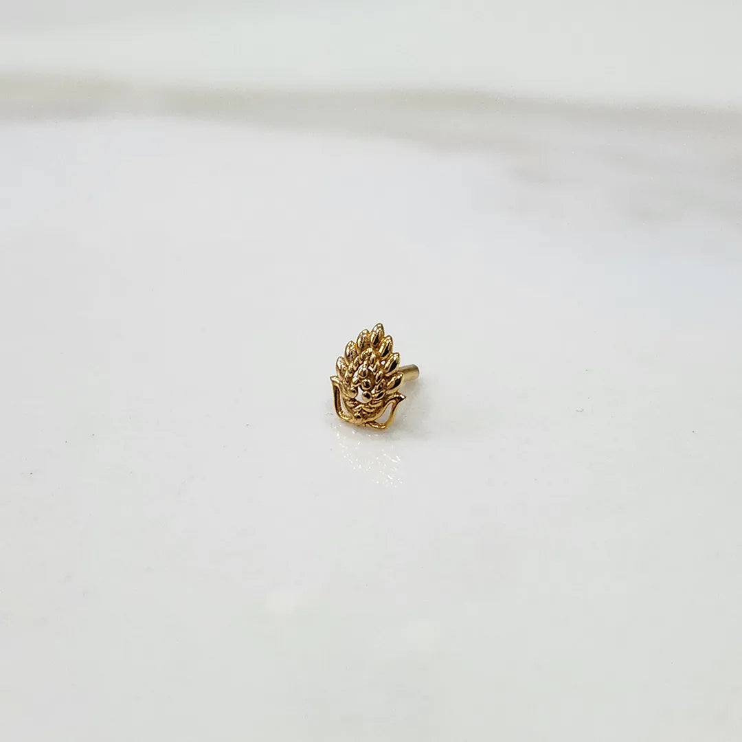 Gold peacock feather nose pin with deity motif, angled view