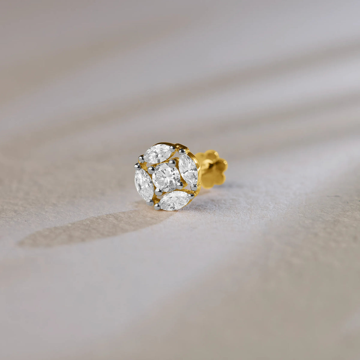 Round floral cluster gold nose pins with marquise and round diamonds on soft background