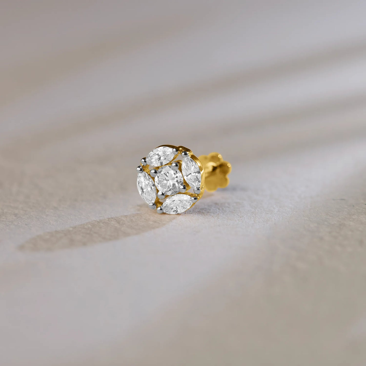 Round floral cluster gold nose pins with marquise and round diamonds on soft background