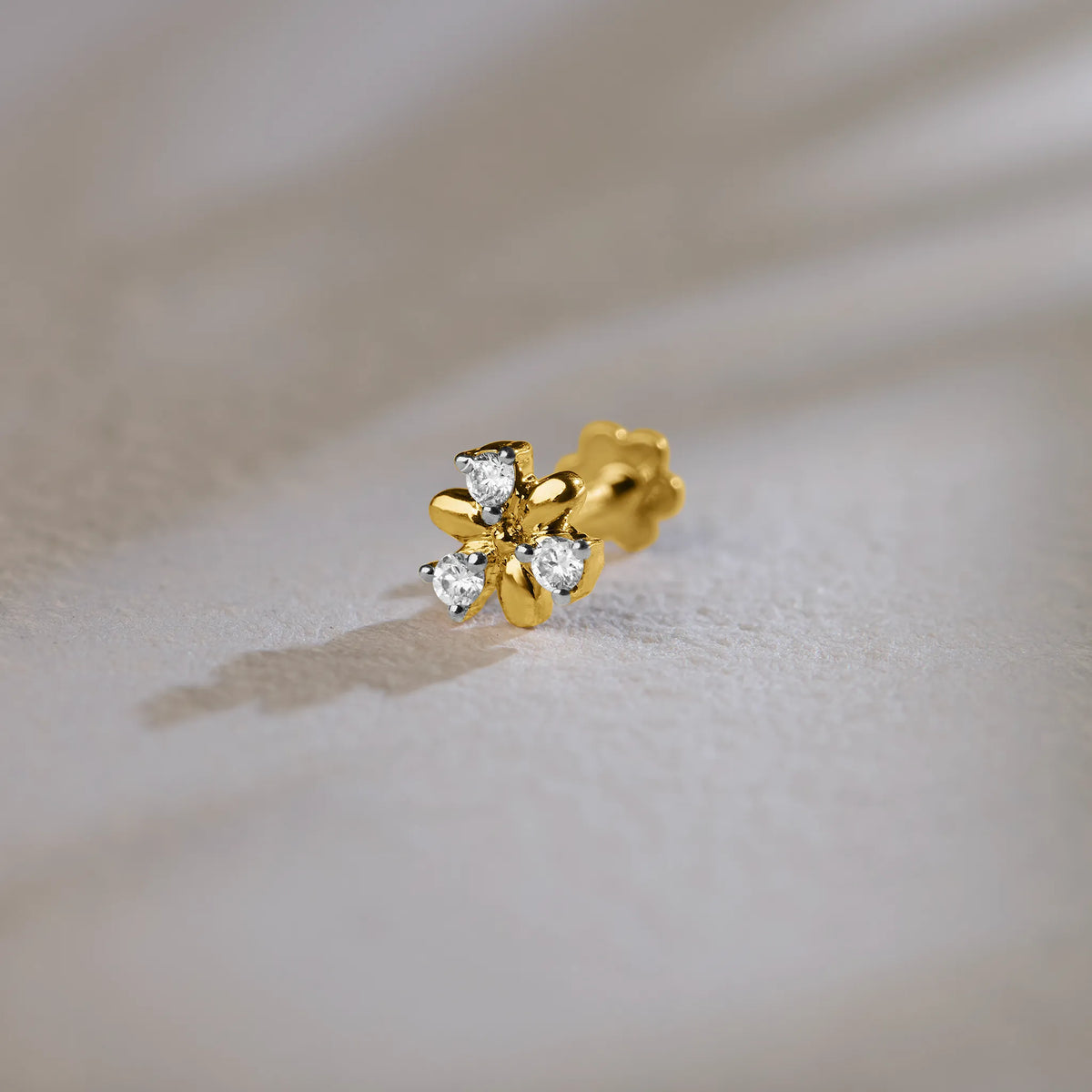 Flower-shaped stud earring with sculpted gold petals and diamond accents
