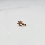 Angled view of gold nose pin with pink gemstone cluster and clear drop-style stone accent on white background