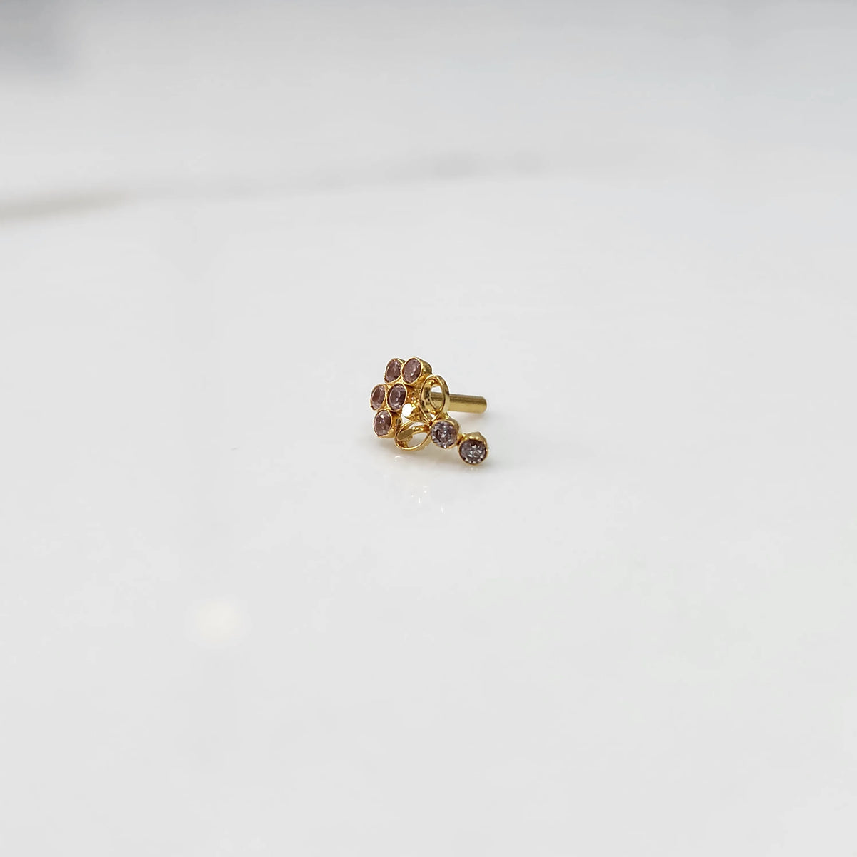 Gold nose pin with pink gemstone cluster and clear drop-style stone accent on white background