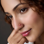 Woman wearing a floral gold nose pin with pink stones
