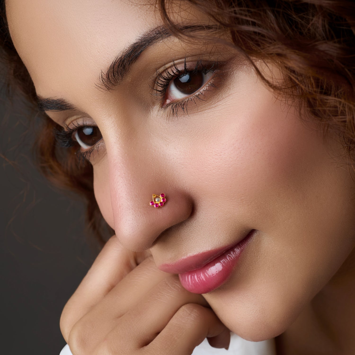 Woman wearing a floral gold nose pin with pink stones