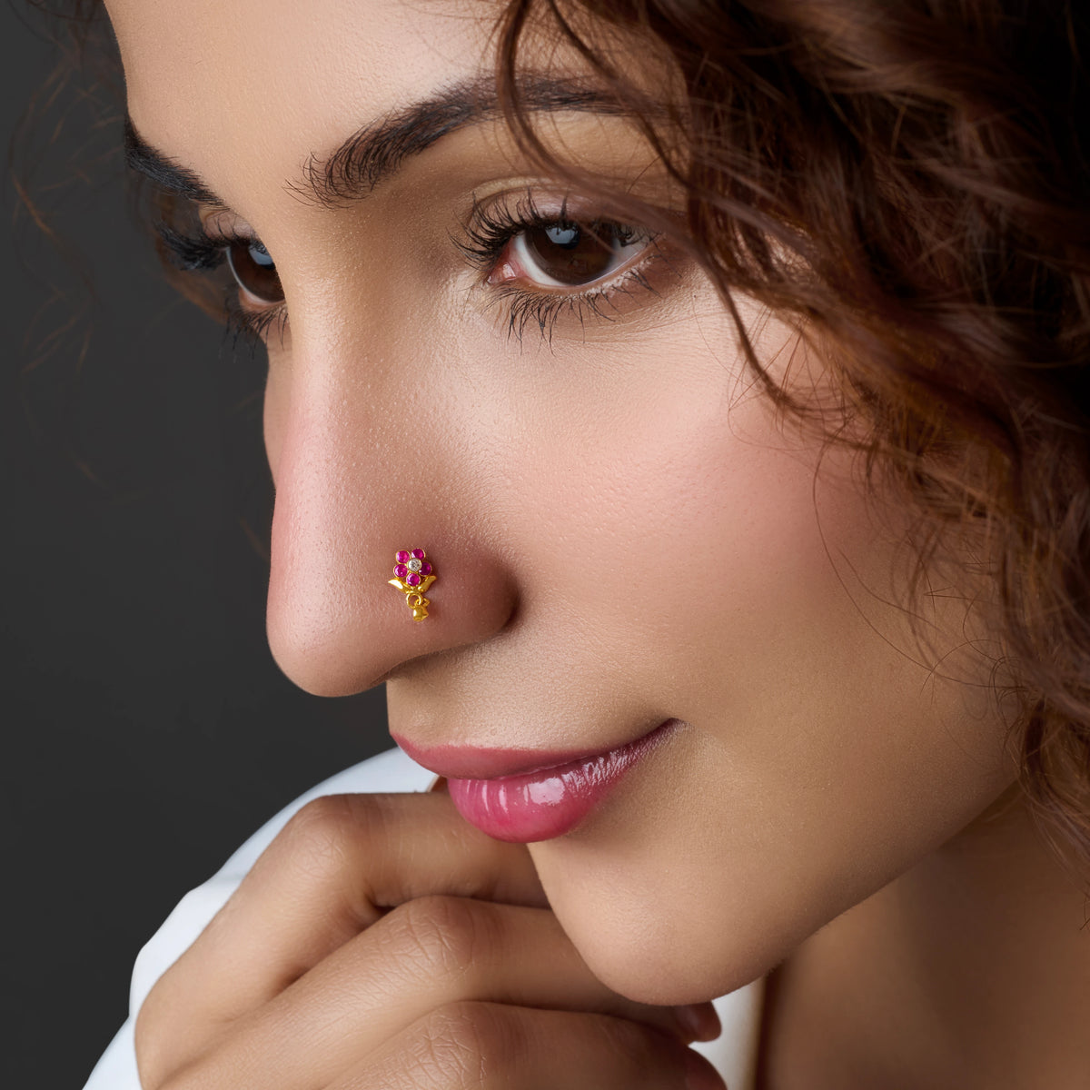 Woman wearing a gold nose pin with pink stone drop