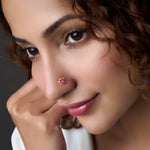 Woman wearing a floral gold nose pin with pink stone center 