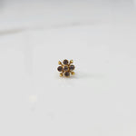 Front view of gold nose pin with pink gemstone flower design on white background