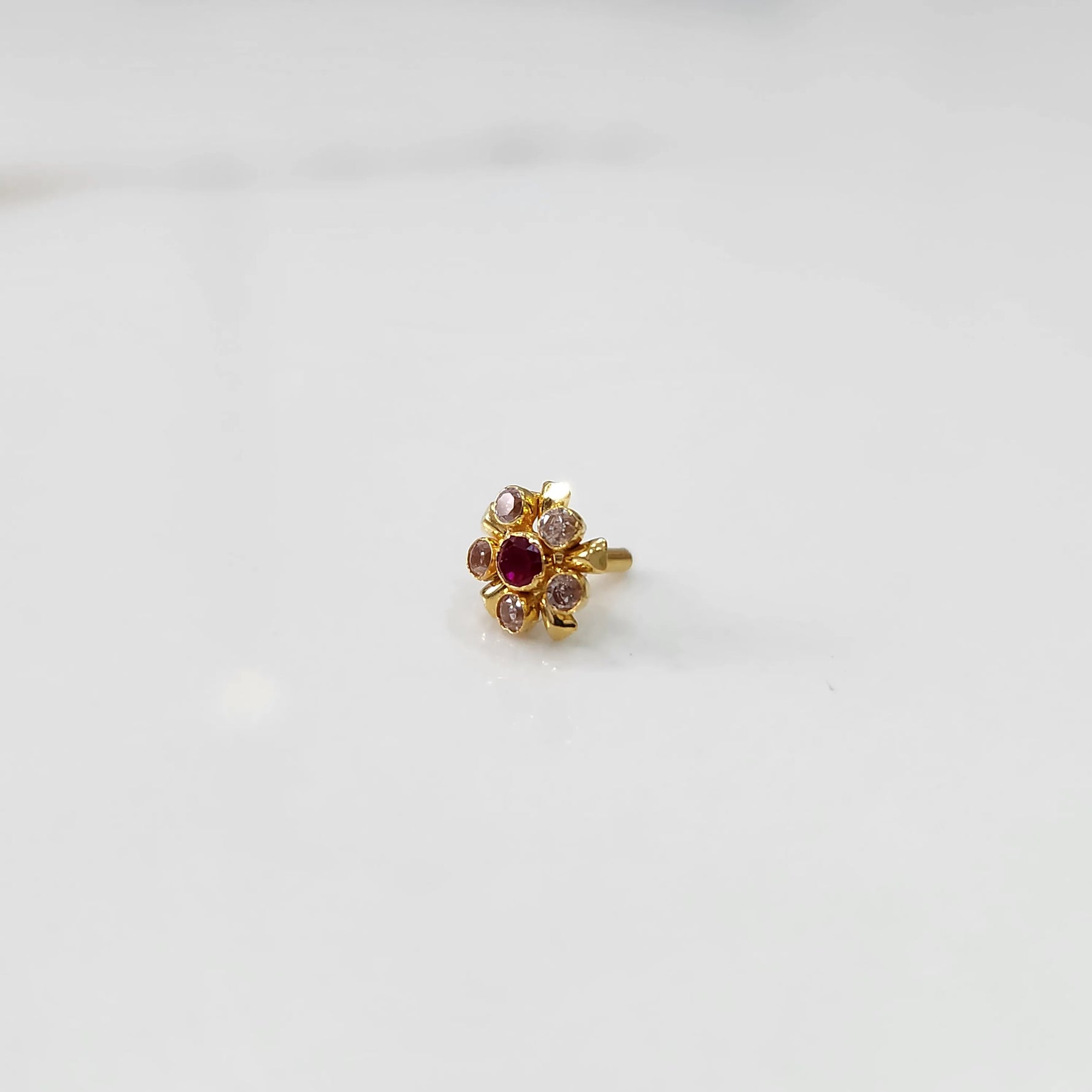 Gold floral nose pin with pink and red stones, product shot