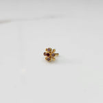 Gold nose pin with pink gemstone petals and red center stone, angled view on white background