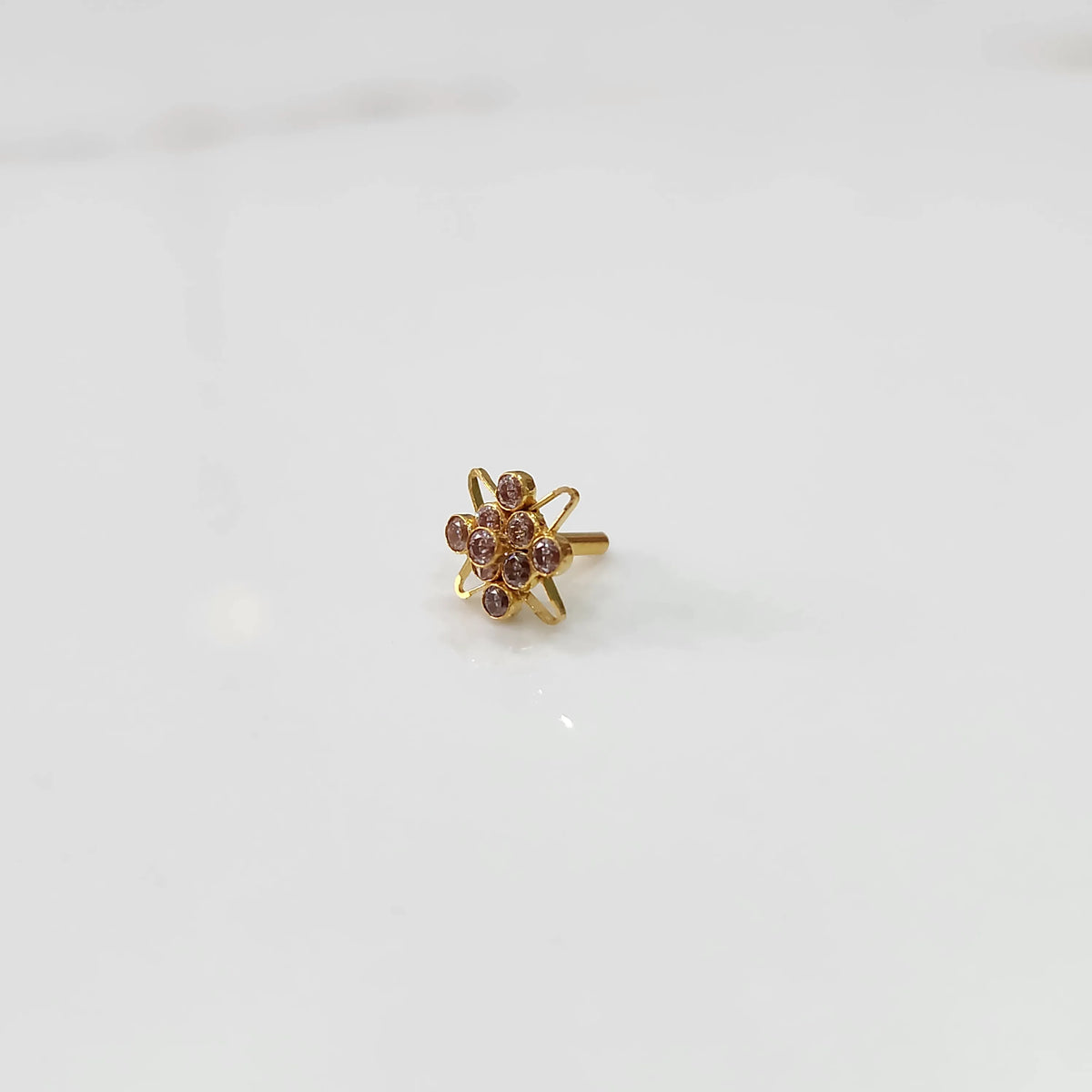 Gold statement ring with pink gemstones in floral starburst design, side angle view