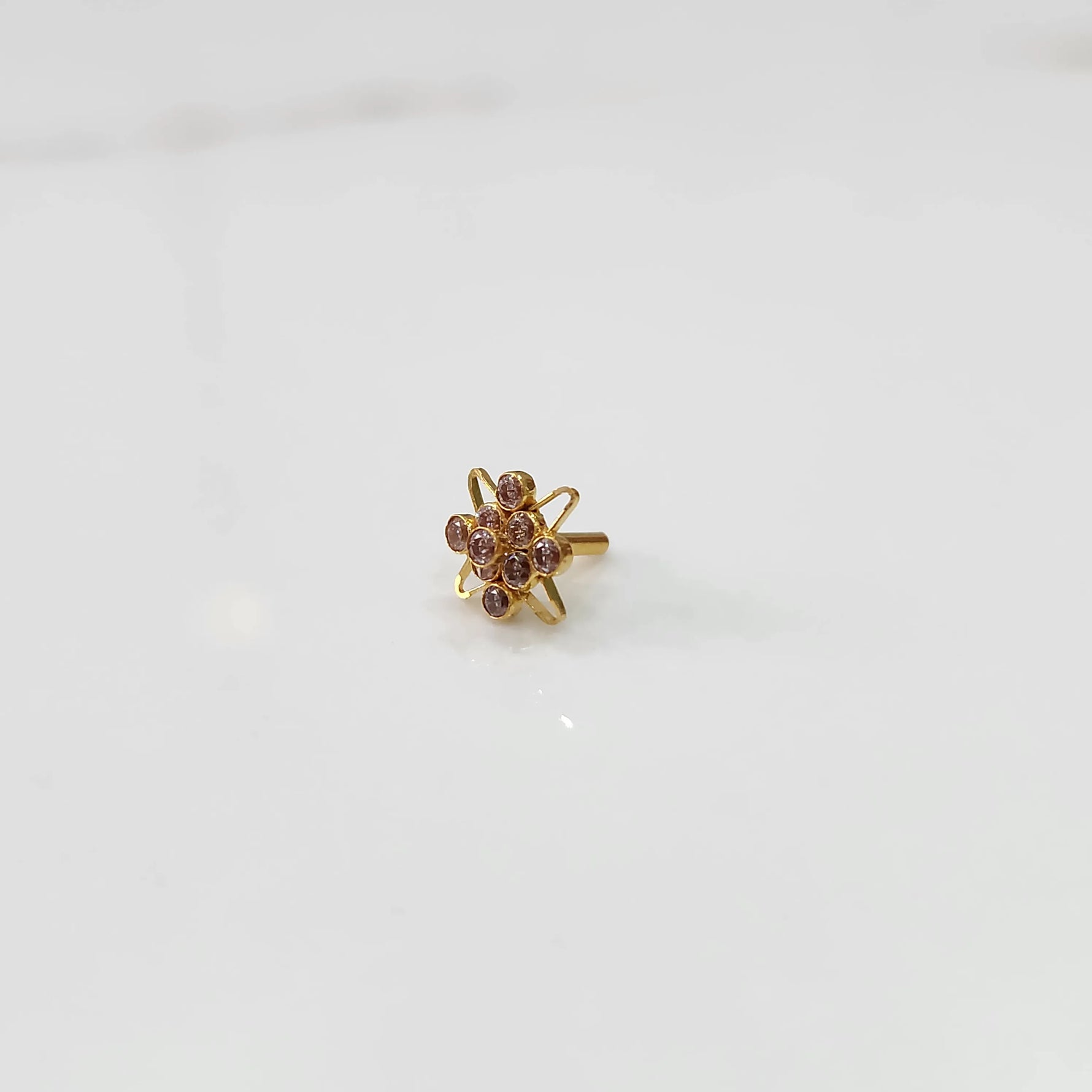 Gold statement ring with pink gemstones in floral starburst design, side angle view