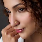 Woman wearing a floral gold nose pin with pink stone