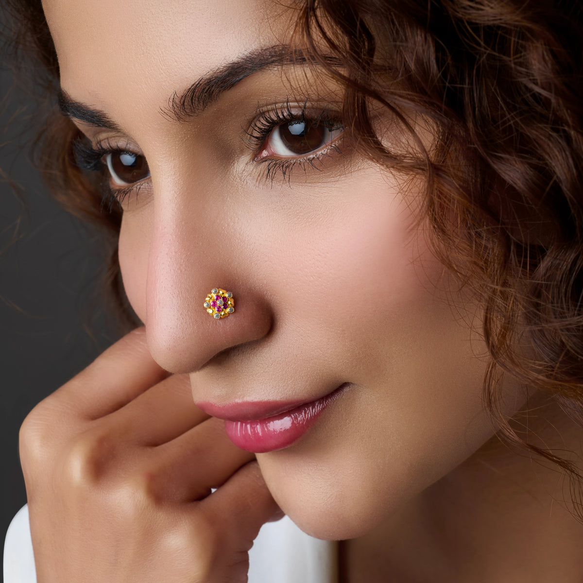 Woman wearing a floral gold nose pin with pink stone