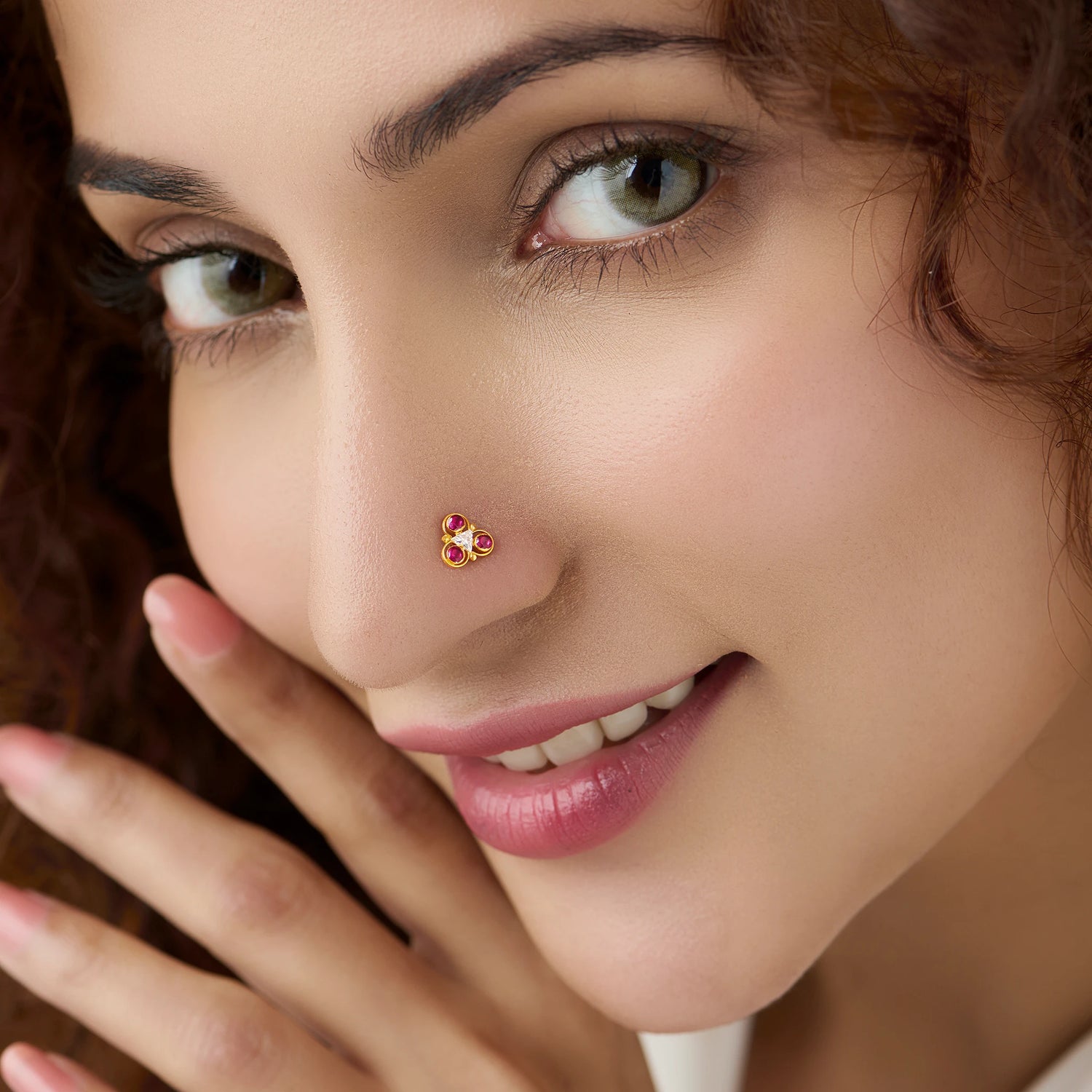 Woman wearing gold trefoil nose pin with pink stones and white center