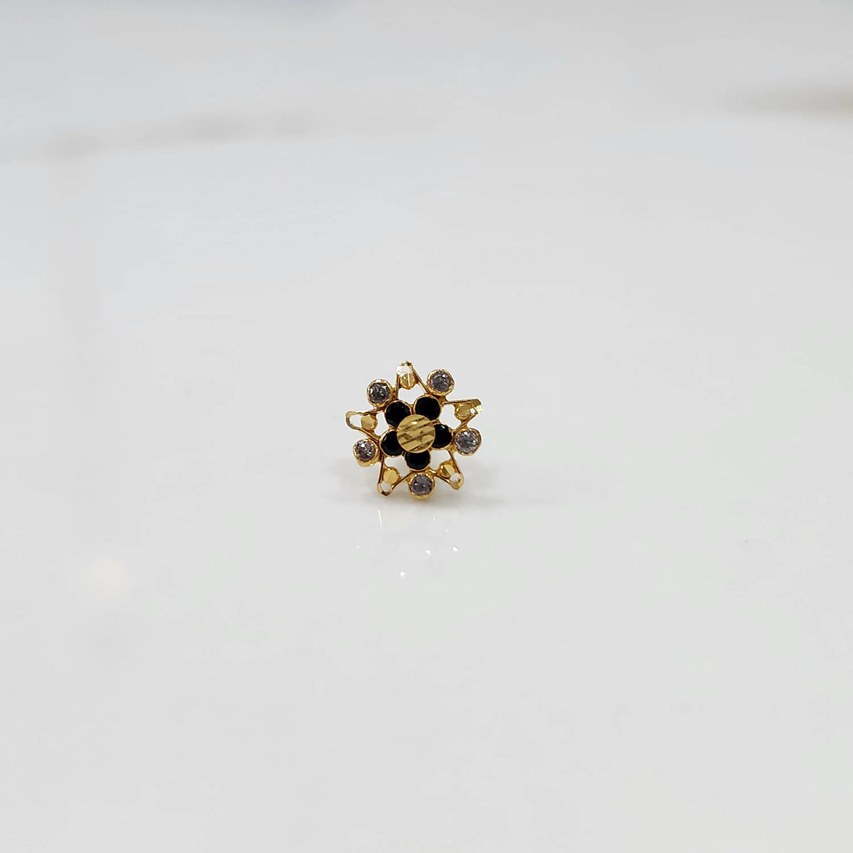 Top view of gold pointed petal ring with black enamel accents