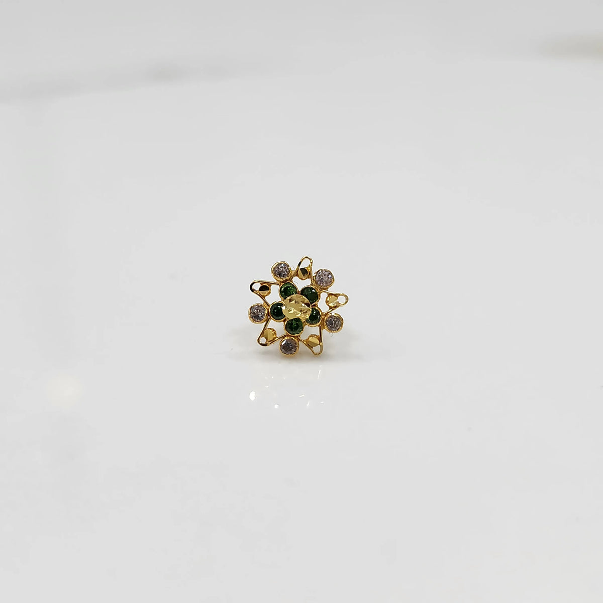 Top view of gold pointed petal ring with green center stones