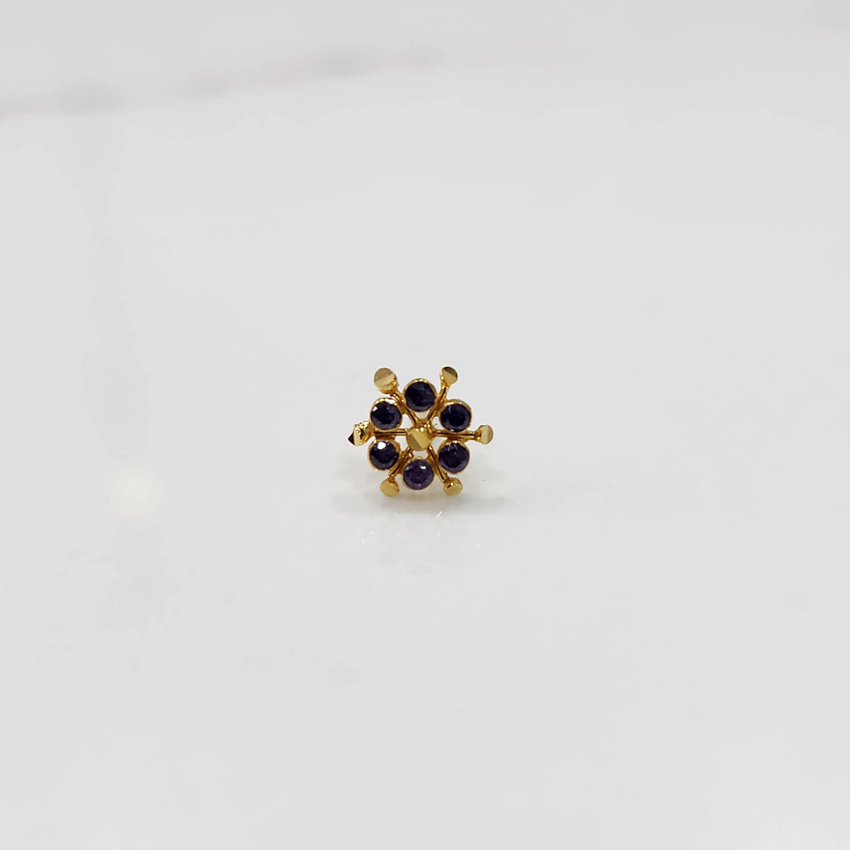 Close-up of gold statement ring with purple cabochon gemstones in scattered cluster design