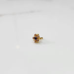 Close-up of flower-shaped gold nose pin with mixed stone colors