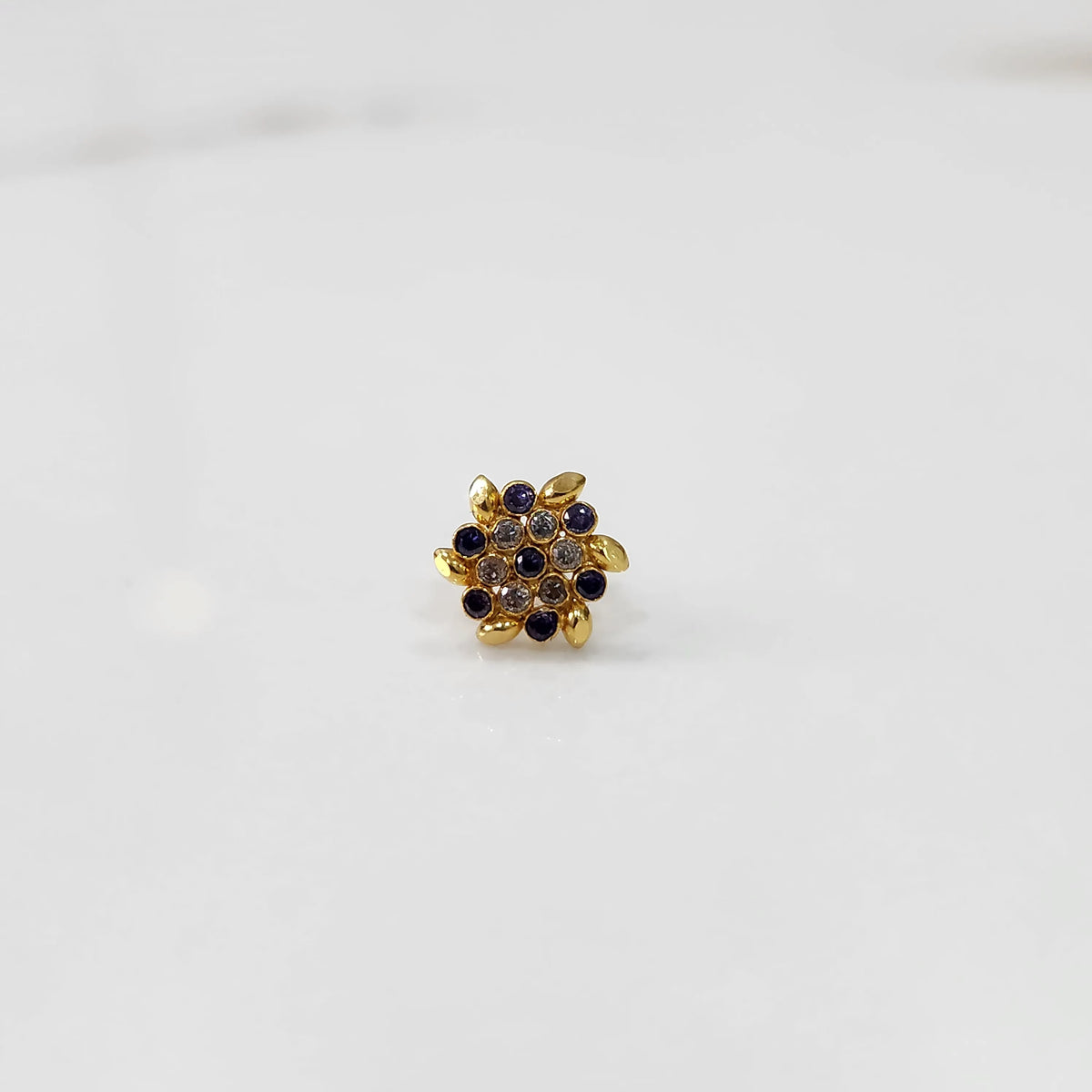 Front view of gold statement ring with purple and clear gemstones in leaf-patterned cluster design