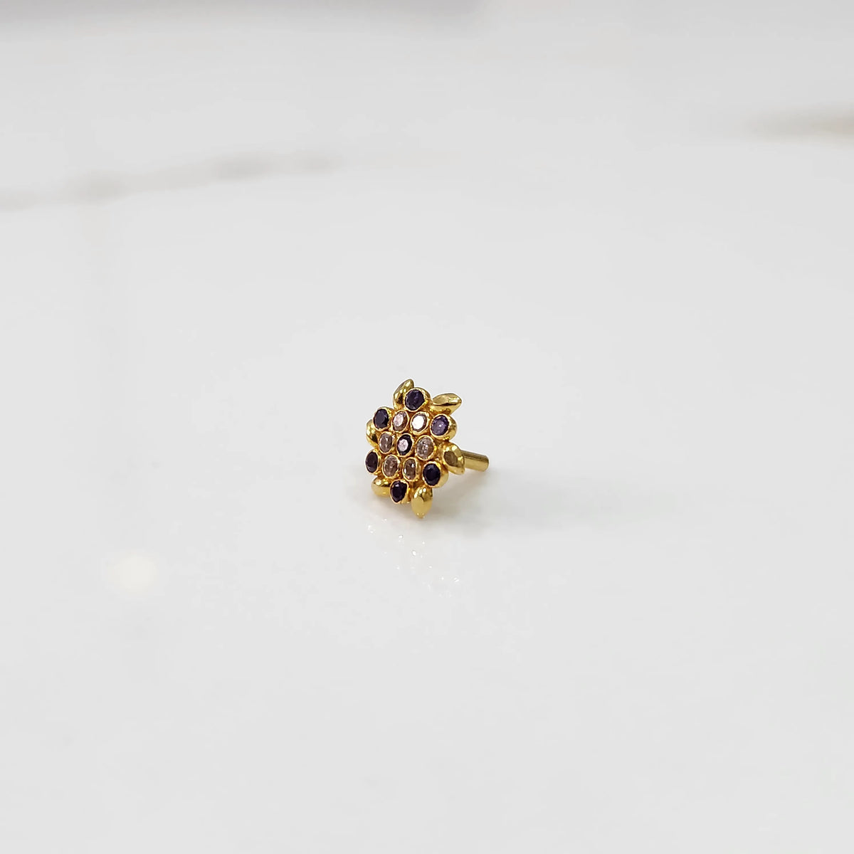 Gold statement ring with purple and clear gemstones in leaf-patterned cluster design