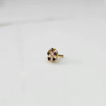 Gold nose pin with purple gemstone petals and clear center stone on white background