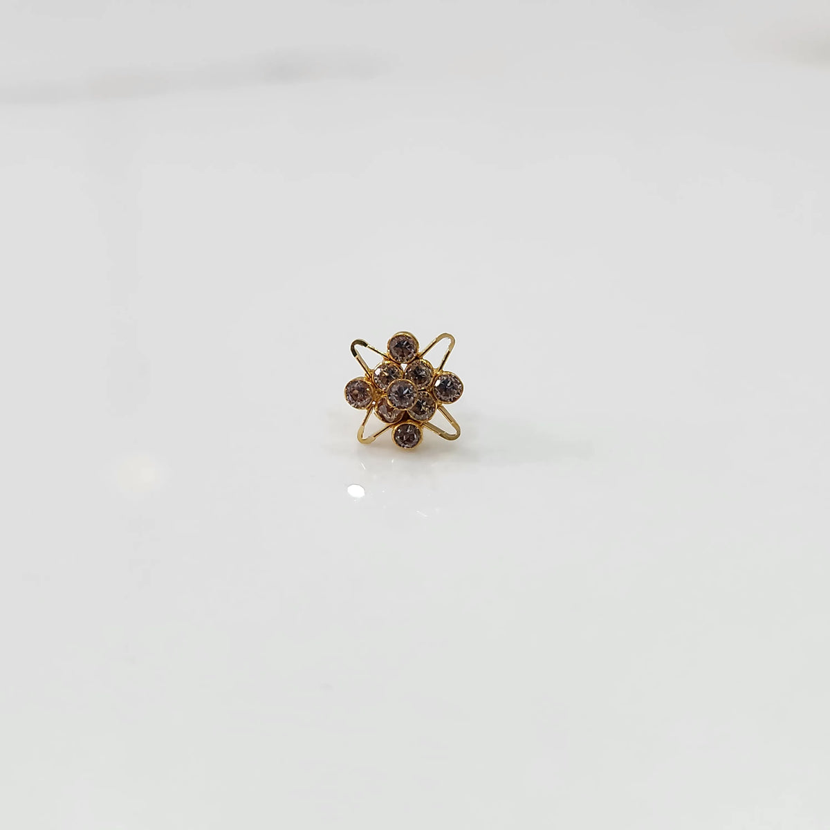 Gold cocktail ring with purple gemstones in atomic-style floral setting