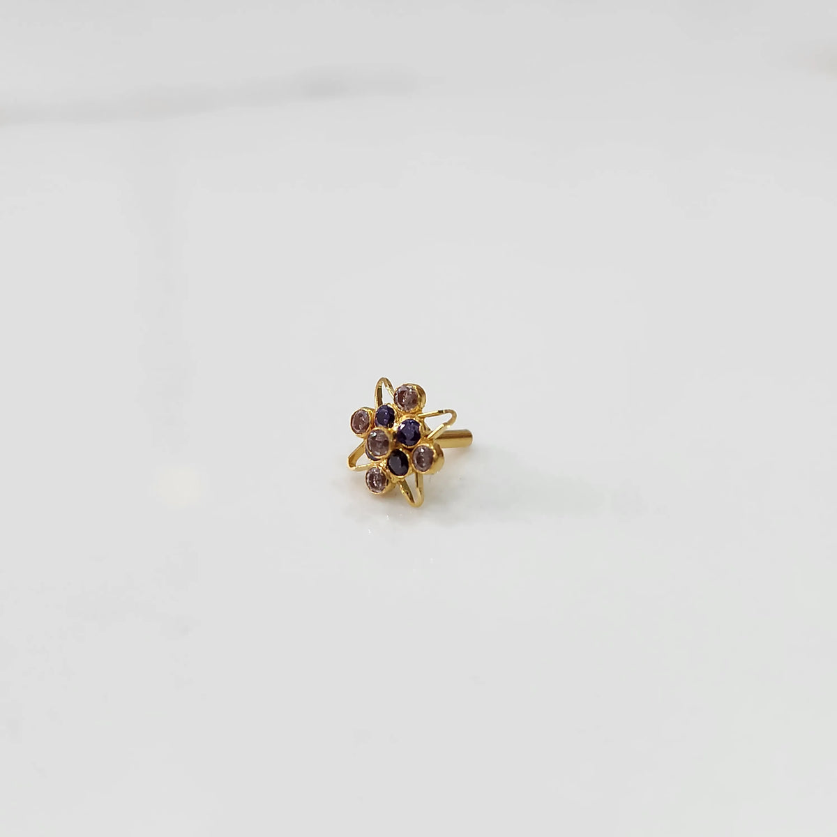 Gold statement ring with purple amethyst-tone gemstones in floral starburst design